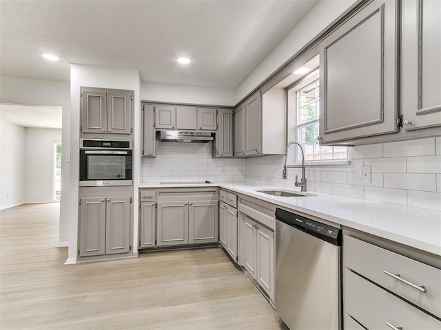 502 Walnut Ave, Yukon, OK 73099 - kitchen featuring appliances with stainless steel finishes, gray cabinetry, light wood-style floors, backsplash, and light countertops