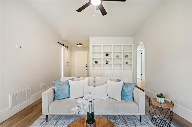 908 NW 12th St, Moore, OK 73160 - living area with a barn door, arched walkways, a ceiling fan, and wood finished floors