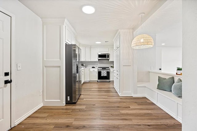 908 NW 12th St, Moore, OK 73160 - kitchen with stainless steel appliances, white cabinets, light wood-style flooring, light countertops, and decorative backsplash