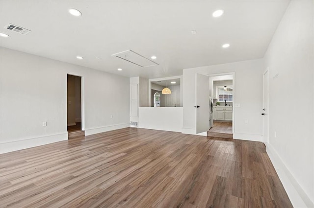 908 NW 12th St, Moore, OK 73160 - unfurnished living room with attic access, wood finished floors, and recessed lighting