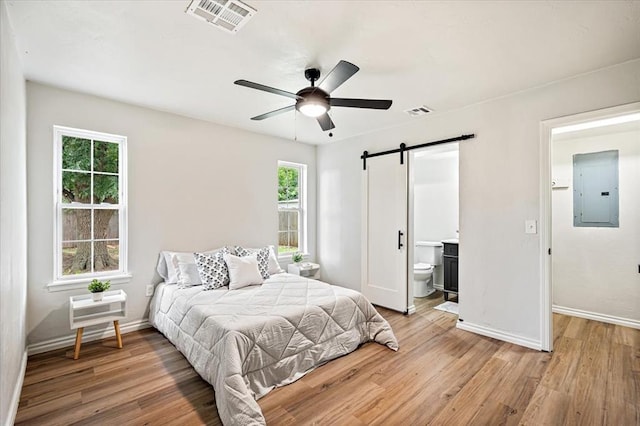 908 NW 12th St, Moore, OK 73160 - bedroom with electric panel, a barn door, light wood-style flooring, and ensuite bathroom