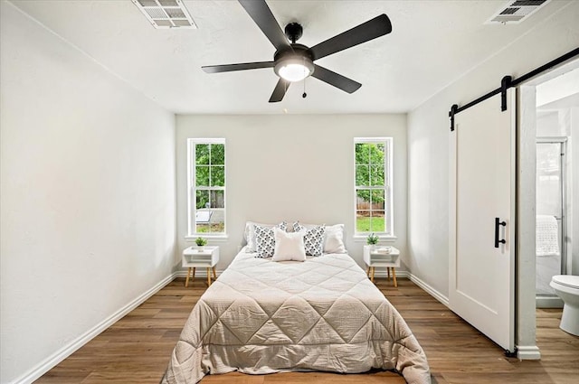 908 NW 12th St, Moore, OK 73160 - bedroom with a barn door, multiple windows, and wood finished floors