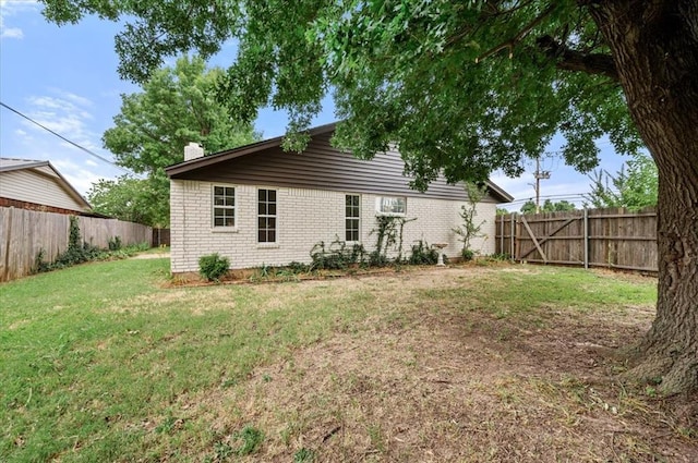 908 NW 12th St, Moore, OK 73160 - back of property featuring brick siding, a fenced backyard, and a chimney