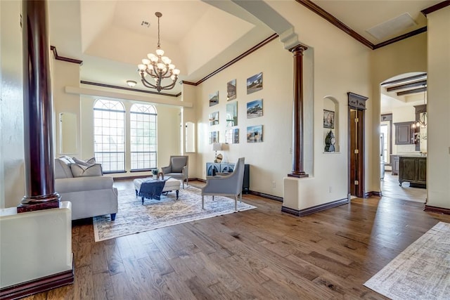 1704 NW 171st St, Edmond, OK 73012 - living room featuring crown molding, ornate columns, a high ceiling, wood finished floors, and a chandelier