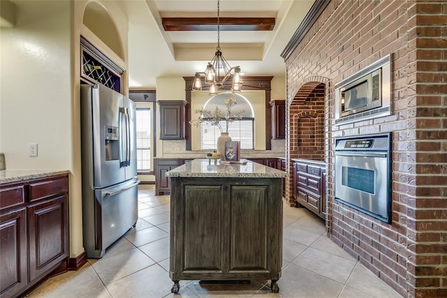 1704 NW 171st St, Edmond, OK 73012 - kitchen featuring appliances with stainless steel finishes, a chandelier, a kitchen island, light tile patterned floors, and beamed ceiling