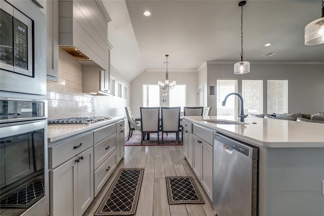 18445 Austin Pl, Edmond, OK 73012 - kitchen featuring appliances with stainless steel finishes, light countertops, lofted ceiling, backsplash, and light wood-style flooring