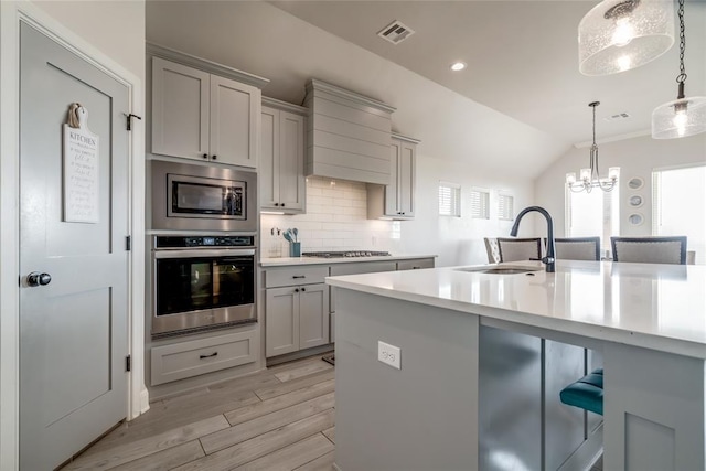 18445 Austin Pl, Edmond, OK 73012 - kitchen featuring stainless steel appliances, gray cabinets, premium range hood, light countertops, and lofted ceiling