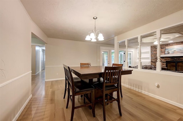 3725 N Grant Ave, Bethany, OK 73008 - dining space with wood finished floors, a textured ceiling, a chandelier, a ceiling fan, and a fireplace