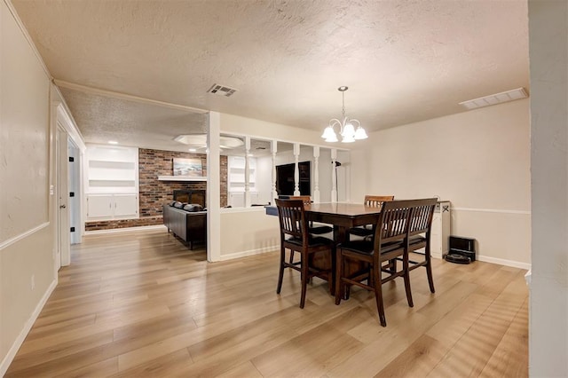 3725 N Grant Ave, Bethany, OK 73008 - dining space featuring a textured ceiling, light wood-style flooring, a chandelier, and a fireplace