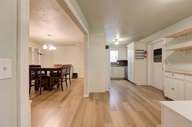 3725 N Grant Ave, Bethany, OK 73008 - kitchen featuring white cabinets, light wood-style floors, a textured ceiling, stainless steel dishwasher, and a chandelier