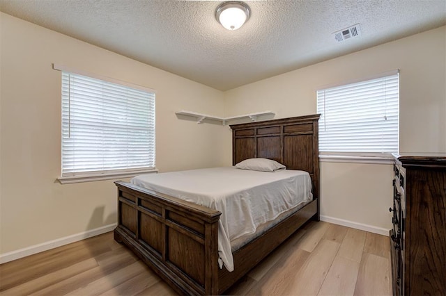 3725 N Grant Ave, Bethany, OK 73008 - bedroom with light wood-type flooring, multiple windows, and a textured ceiling