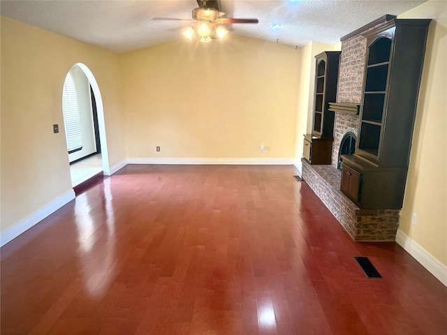 2608 SW 93rd, Oklahoma City, OK 73159 - unfurnished living room featuring ceiling fan, dark wood-style flooring, a brick fireplace, a textured ceiling, and built in shelves