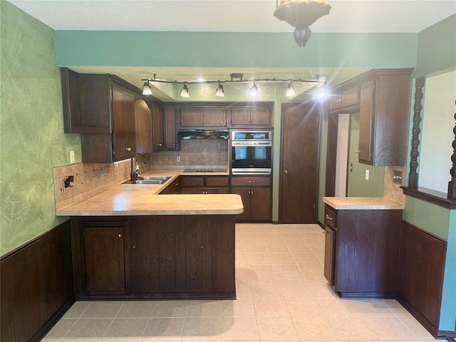 2608 SW 93rd, Oklahoma City, OK 73159 - kitchen featuring oven, under cabinet range hood, light countertops, dark brown cabinetry, and wainscoting