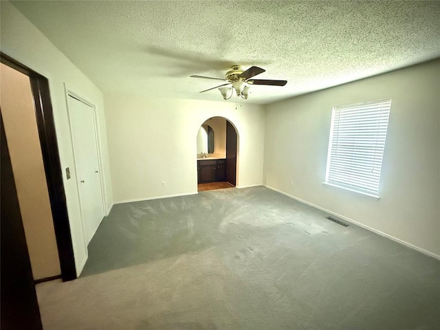 2608 SW 93rd, Oklahoma City, OK 73159 - unfurnished bedroom with arched walkways, carpet, a textured ceiling, ensuite bathroom, and ceiling fan