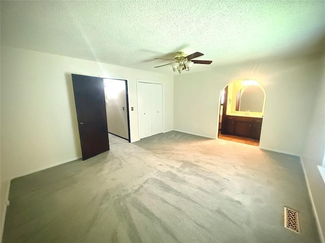 2608 SW 93rd, Oklahoma City, OK 73159 - unfurnished bedroom with arched walkways, carpet flooring, a textured ceiling, two closets, and ceiling fan