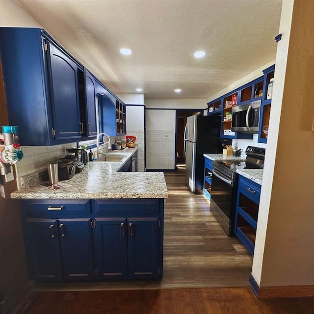 701 S 18th St, Clinton, OK 73601 - kitchen featuring appliances with stainless steel finishes, blue cabinets, open shelves, dark wood-type flooring, and a peninsula
