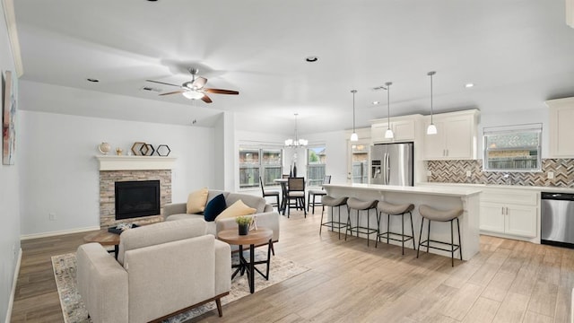 3021 NW 179th Ct, Edmond, OK 73012 - living room featuring a ceiling fan, a stone fireplace, light wood-style floors, plenty of natural light, and recessed lighting