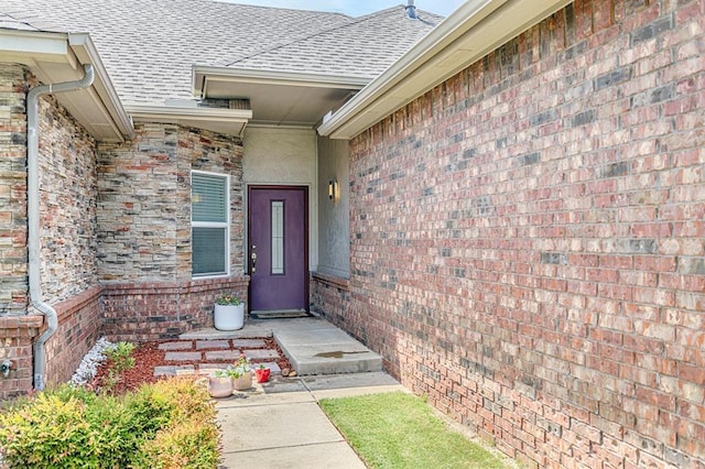 17425 White Hawk Dr, Edmond, OK 73012 - view of exterior entry featuring a shingled roof, stucco siding, and brick siding