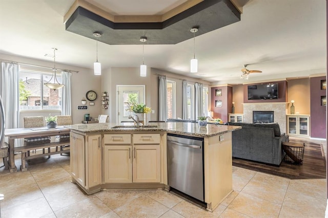 17425 White Hawk Dr, Edmond, OK 73012 - kitchen featuring dishwasher, light tile patterned flooring, a ceiling fan, a glass covered fireplace, and light stone countertops