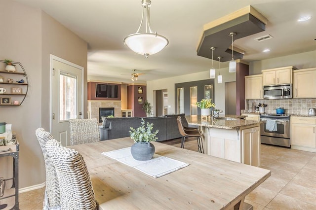 17425 White Hawk Dr, Edmond, OK 73012 - dining space with a tile fireplace, a ceiling fan, and light tile patterned flooring