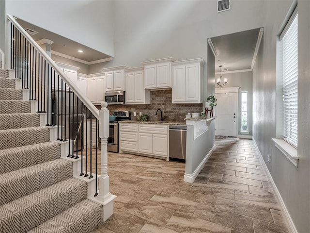 4800 Stelens Ct, Norman, OK 73071 - kitchen featuring stainless steel appliances, a high ceiling, tasteful backsplash, ornamental molding, and white cabinetry