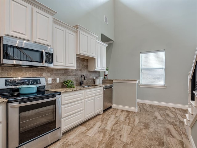 4800 Stelens Ct, Norman, OK 73071 - kitchen with stainless steel appliances, a high ceiling, white cabinets, tasteful backsplash, and light stone counters