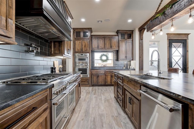 8960 N Banner Rd, Yukon, OK 73099 - kitchen featuring stainless steel appliances, custom range hood, light wood-type flooring, decorative backsplash, and glass insert cabinets