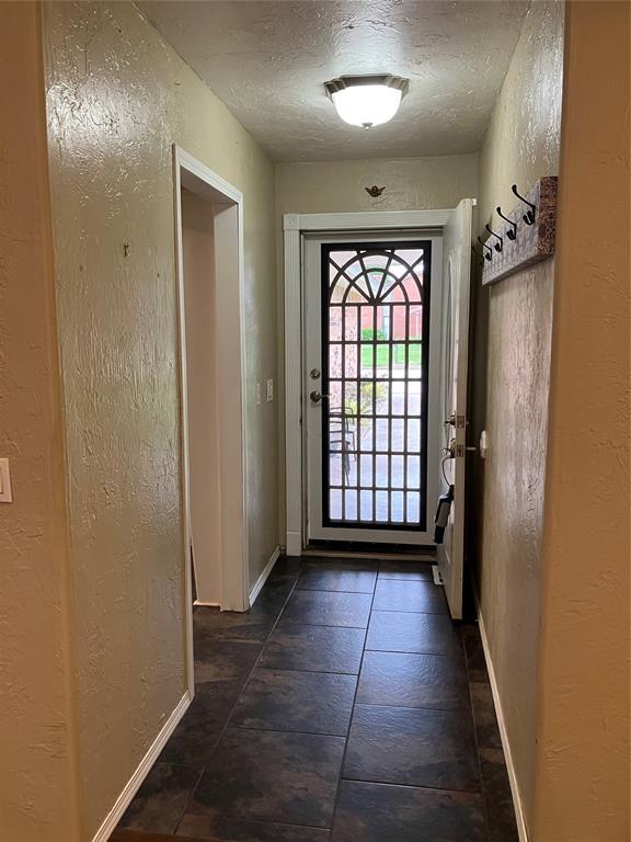 9105 Oak Creek Dr, Midwest City, OK 73130 - doorway to outside featuring a textured wall and a textured ceiling