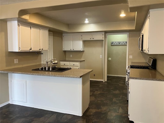 9105 Oak Creek Dr, Midwest City, OK 73130 - kitchen with gas range oven, a peninsula, white cabinetry, stainless steel microwave, and dark countertops