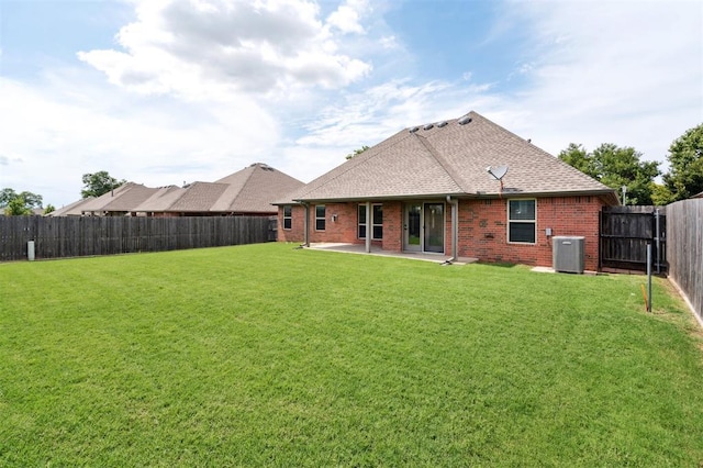 9024 NW 79th Ter, Yukon, OK 73099 - rear view of property featuring brick siding, a patio, a fenced backyard, and roof with shingles