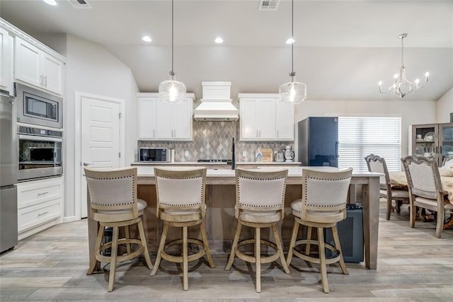14812 Deerbrook Blvd, Oklahoma City, OK 73142 - kitchen featuring appliances with stainless steel finishes, custom range hood, vaulted ceiling, decorative backsplash, and light countertops