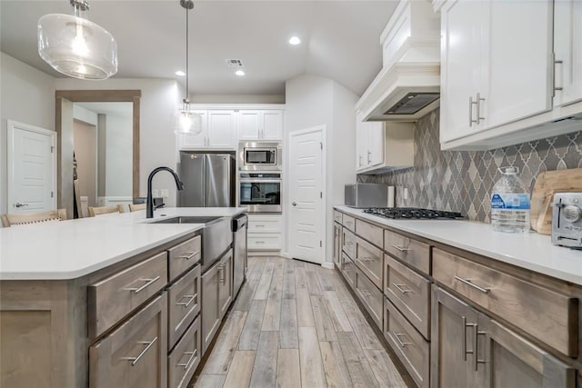 14812 Deerbrook Blvd, Oklahoma City, OK 73142 - kitchen featuring stainless steel appliances, premium range hood, light wood finished floors, decorative backsplash, and light countertops