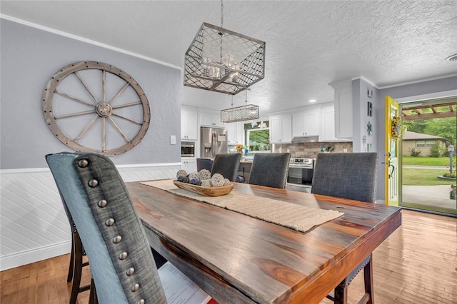 1800 SW 6th St, Ardmore, OK 73401 - dining room with wainscoting, a textured ceiling, and light wood-style flooring