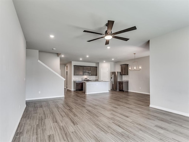 4205 Palmetto Bluff Dr, Mustang, OK 73064 - unfurnished living room featuring ceiling fan, wood finished floors, recessed lighting, and a chandelier