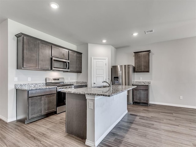 4205 Palmetto Bluff Dr, Mustang, OK 73064 - kitchen featuring appliances with stainless steel finishes, light stone countertops, wood finished floors, dark brown cabinetry, and recessed lighting