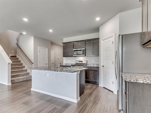 4205 Palmetto Bluff Dr, Mustang, OK 73064 - kitchen featuring stainless steel appliances, light wood-type flooring, dark brown cabinetry, light stone countertops, and recessed lighting