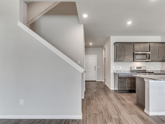 4205 Palmetto Bluff Dr, Mustang, OK 73064 - kitchen with appliances with stainless steel finishes, wood finished floors, dark brown cabinetry, recessed lighting, and light stone counters