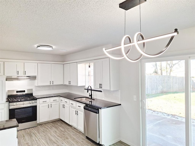 4713 Meench Dr, Del City, OK 73115 - kitchen with stainless steel appliances, under cabinet range hood, dark countertops, a textured ceiling, and tasteful backsplash
