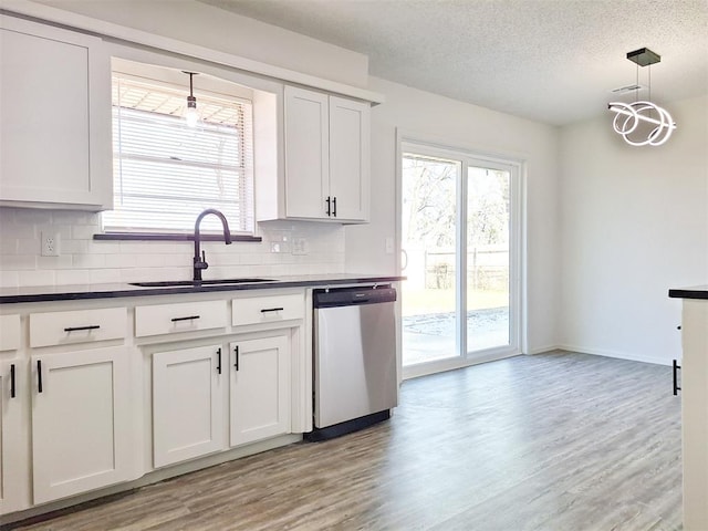 4713 Meench Dr, Del City, OK 73115 - kitchen with stainless steel dishwasher, dark countertops, backsplash, light wood finished floors, and a textured ceiling