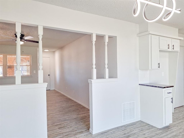 4713 Meench Dr, Del City, OK 73115 - kitchen with light wood-type flooring, white cabinetry, a ceiling fan, dark countertops, and a textured ceiling