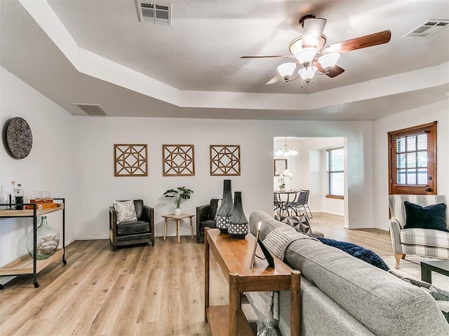17 Pueblo, Edmond, OK 73013 - living area featuring a raised ceiling, a ceiling fan, light wood-style floors, and a chandelier