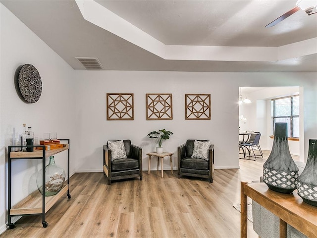 17 Pueblo, Edmond, OK 73013 - living area featuring light wood-style flooring, a raised ceiling, and ceiling fan