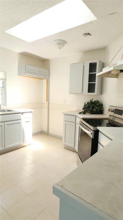 537 NW 114th St, Oklahoma City, OK 73114 - kitchen featuring stainless steel range with electric stovetop, light countertops, open shelves, extractor fan, and light tile patterned flooring