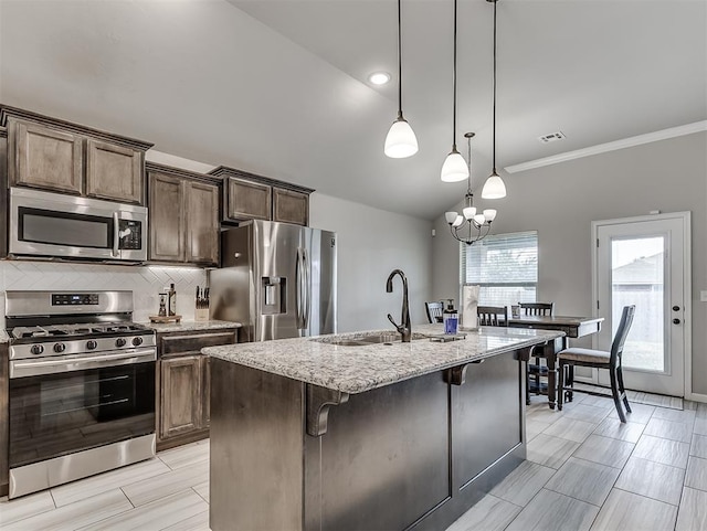 11604 SW 9th St, Yukon, OK 73099 - kitchen with stainless steel appliances, light stone countertops, backsplash, a center island with sink, and hanging light fixtures