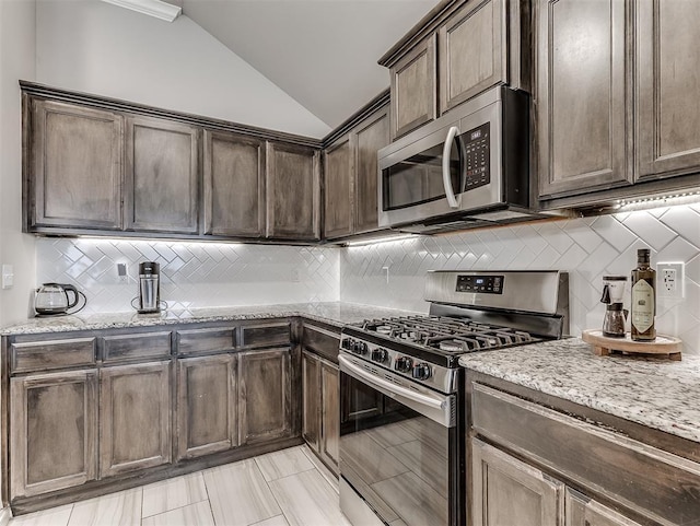11604 SW 9th St, Yukon, OK 73099 - kitchen with appliances with stainless steel finishes, vaulted ceiling, tasteful backsplash, light stone countertops, and dark brown cabinetry