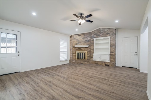 7913 Debar Cir, Oklahoma City, OK 73132 - unfurnished living room with vaulted ceiling, ceiling fan, built in features, wood finished floors, and a fireplace