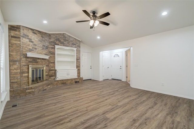 7913 Debar Cir, Oklahoma City, OK 73132 - unfurnished living room featuring vaulted ceiling, ceiling fan, a fireplace, wood finished floors, and built in shelves