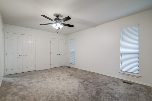 7913 Debar Cir, Oklahoma City, OK 73132 - unfurnished bedroom with two closets, carpet floors, and a ceiling fan