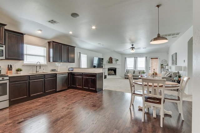 11316 NW 94th St, Yukon, OK 73099 - kitchen with stainless steel appliances, dark brown cabinets, open floor plan, a ceiling fan, and a fireplace