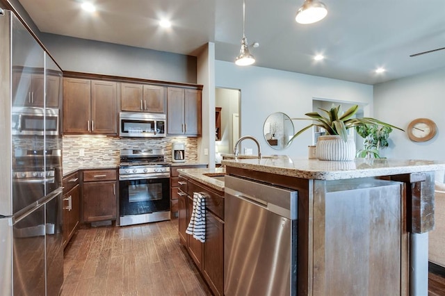 9124 NW 90th Cir, Yukon, OK 73099 - kitchen with stainless steel appliances, dark wood-style floors, tasteful backsplash, light stone countertops, and a center island with sink
